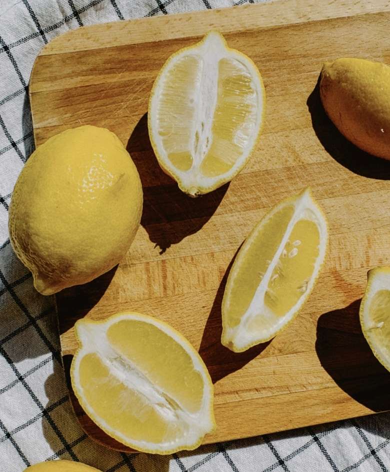 Detalle de limones naturales, enteros y cortados, preparados para uso culinario